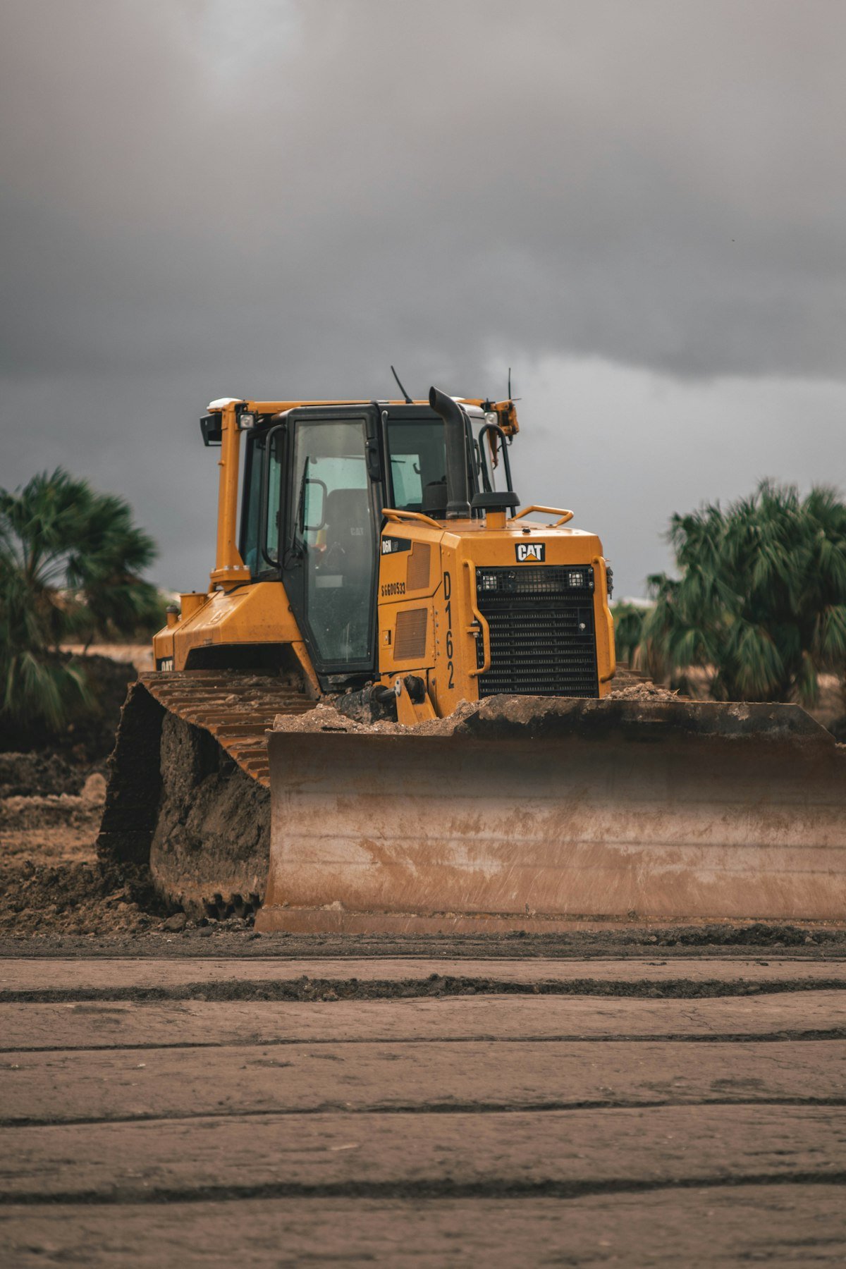 Bulldozer clearing earth on a construction site under a stormy sky