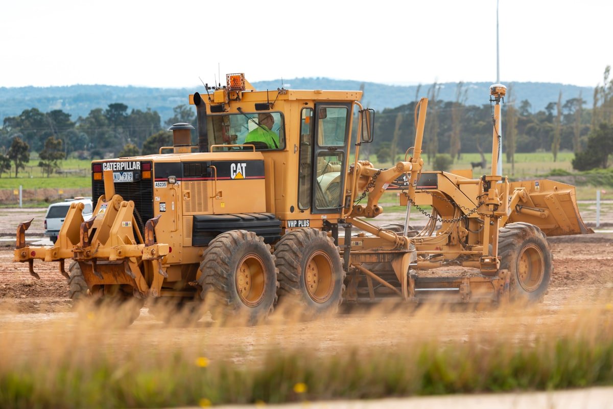 Motor grader levelling a road surface in bright daylight